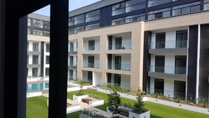 A modern building with multiple balconies and a courtyard with artificial grass and planters.