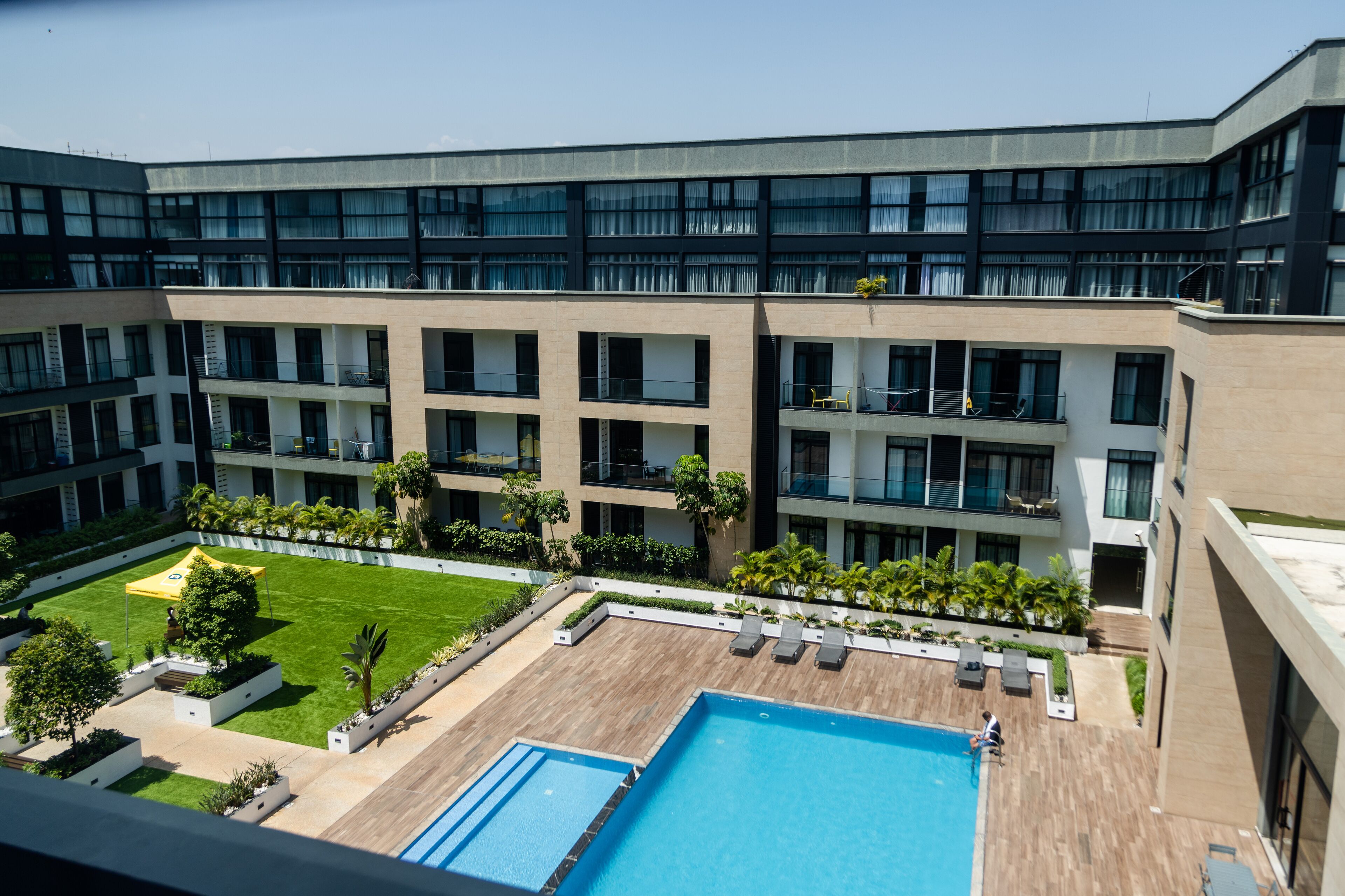 A modern hotel with a rooftop pool, multiple balconies, and a well-maintained courtyard.