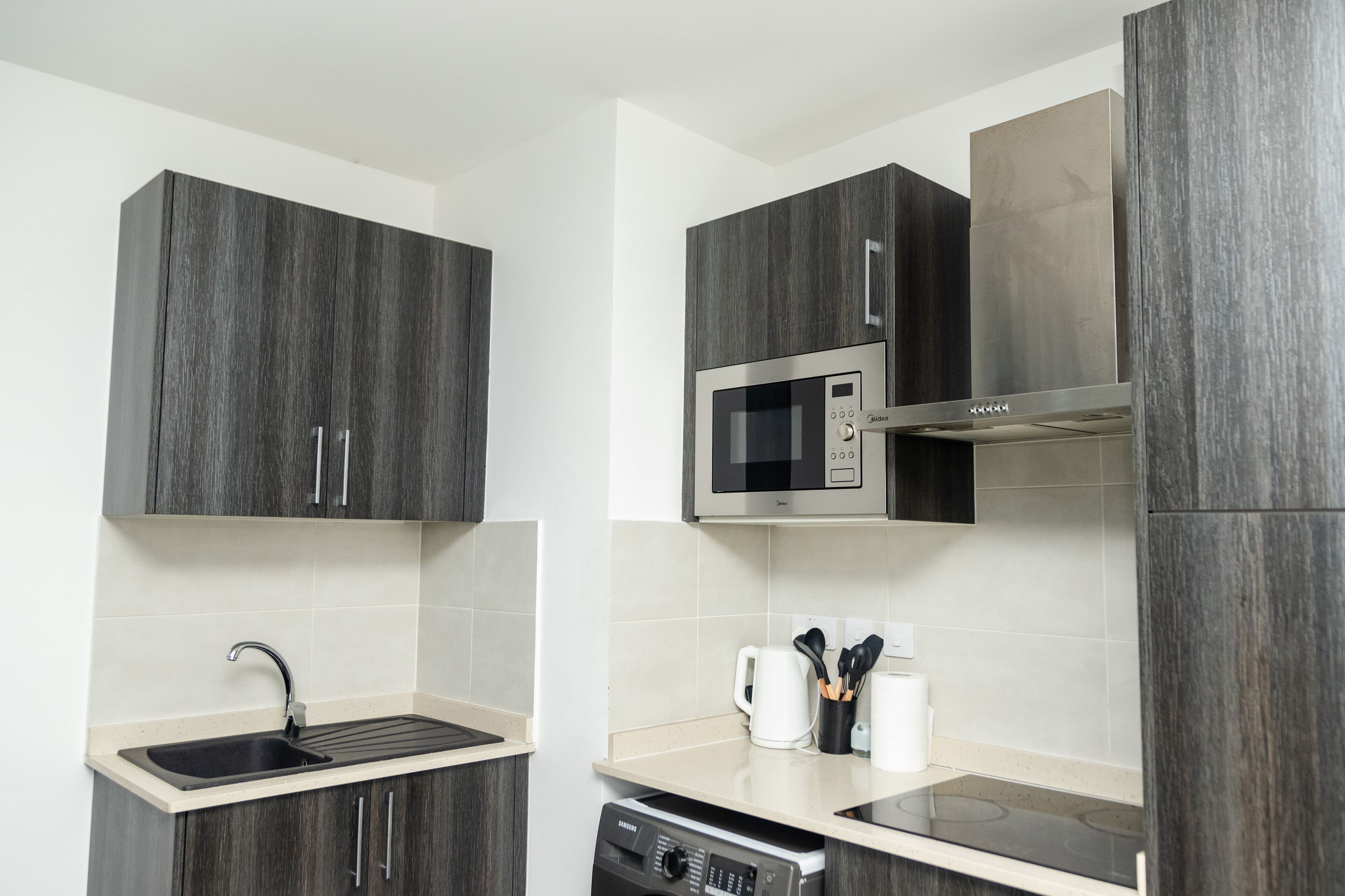A modern kitchen with dark wood cabinets, a stainless steel microwave, and a dishwasher.