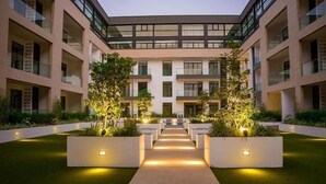 A modern building with a central courtyard, featuring a symmetrical design with two large planters on either side of a central walkway.
