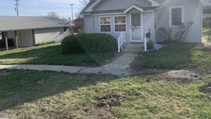 Een gelijkvloers huis met een veranda, garage en een kleine voortuin.