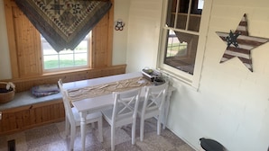 Een knus vertrek met een houten bank, een witte tafel met stoelen, een raam met uitzicht en een ster decoratie aan de muur.