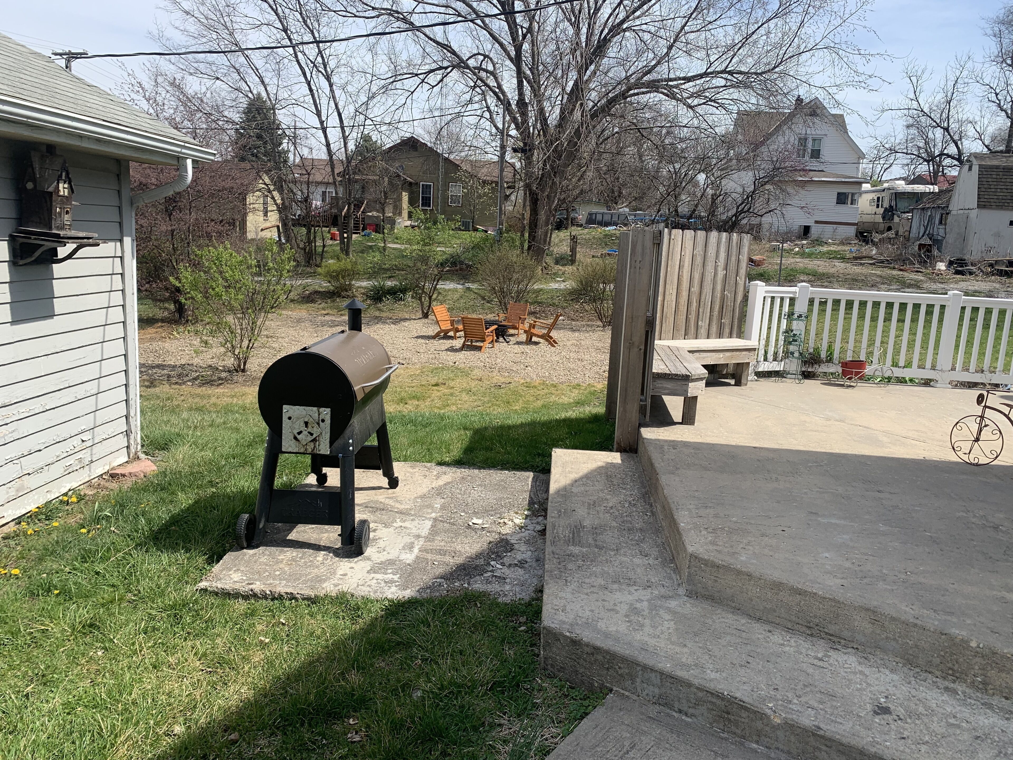 Un jardin avec un barbecue, du mobilier d’extérieur et une clôture en bois.