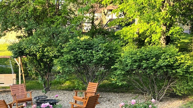 Een tuin met houten stoelen, een tafel en peonia's.