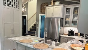 A modern kitchen with a marble countertop, stainless steel appliances, and a built-in island with stools.