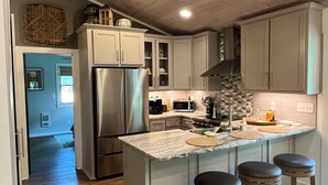 A modern kitchen with wooden cabinets, a stainless steel refrigerator, and a central island with stools.