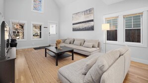 A spacious living room with a high ceiling, a large window, and a modern sofa.