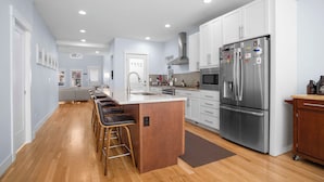 A modern kitchen with a central island, stainless steel appliances, and a bar seating area.