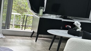 En moderne stue med et fladskærms-tv, et lille rundt bord og en grå, blød måtte.