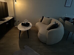 A modern living room with a sofa, a coffee table, and a dining area with chairs.