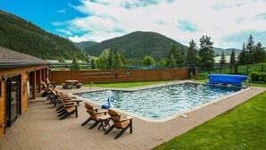 A pool area with lounge chairs, a wooden deck, and a view of mountains. - One block to Keystone Conference Ctr: 2-BR townhouse, king beds, pool, hot tub (Keystone)