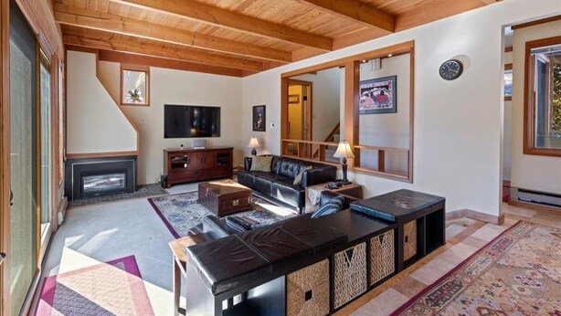 A spacious living room with a fireplace, wooden ceiling beams, a large mirror, and a television. - One block to Keystone Conference Ctr: 2-BR townhouse, king beds, pool, hot tub (Keystone)