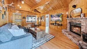 A wooden interior with a fireplace, a sofa, and a television. - Cozy Cabin Nestled in the Wilderness - 1 mile from Bear mountain (Big Bear Lake)