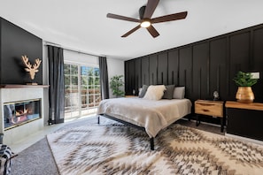 Relax in this serene bedroom with a large bed, fireplace, and stunning outdoor views.