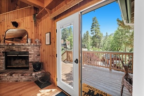 Enjoy a cozy atmosphere with a fireplace and outdoor deck offering a view of the surrounding forest.