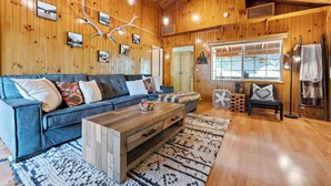 A cozy living room with a blue sofa, wooden coffee table, and a patterned rug. - Cozy Cabin Nestled in the Wilderness - 1 mile from Bear mountain (Big Bear Lake)