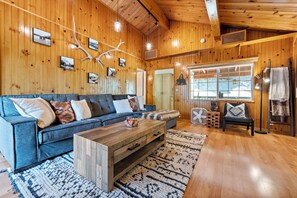 Relax in this inviting living room with a comfortable sofa, coffee table, and large window offering a view of the outdoors.