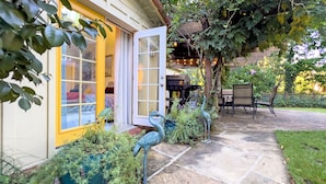 A house with a yellow door and a window, a patio with chairs, and a bird sculpture. - Reflections Main House + 3 Cottages w/Baths + Hot Tub, Pool & Dog Friendly (Guerneville)