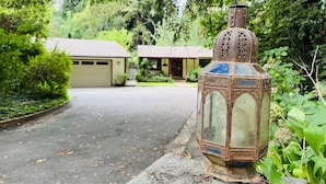 A rustic lantern on a concrete base, a driveway leading to a house, and lush greenery in the background. - Reflections Main House + 3 Cottages w/Baths + Hot Tub, Pool & Dog Friendly (Guerneville)