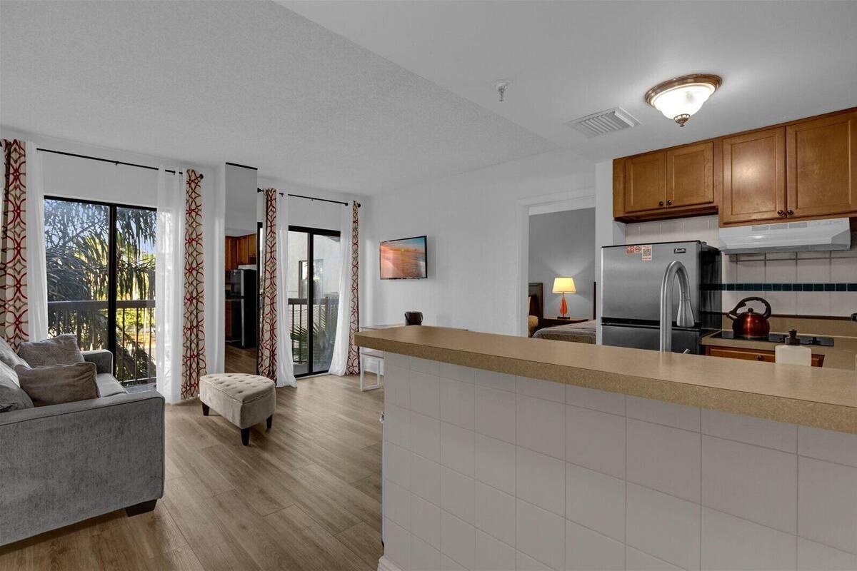 A modern kitchen with a built-in island, wooden cabinets, and a stainless steel refrigerator.