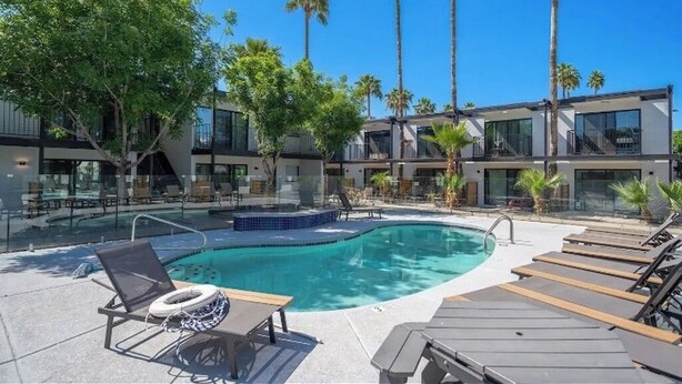 Un hôtel moderne doté d’une piscine, de chaises longues et de palmiers.