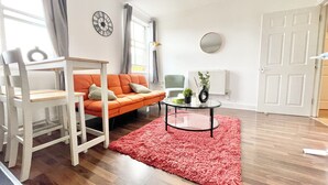 A living room with a sofa, a chair, a coffee table, and a red rug.