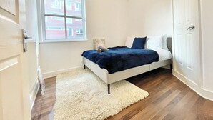 A bedroom with a bed, a window, a radiator, and a door.