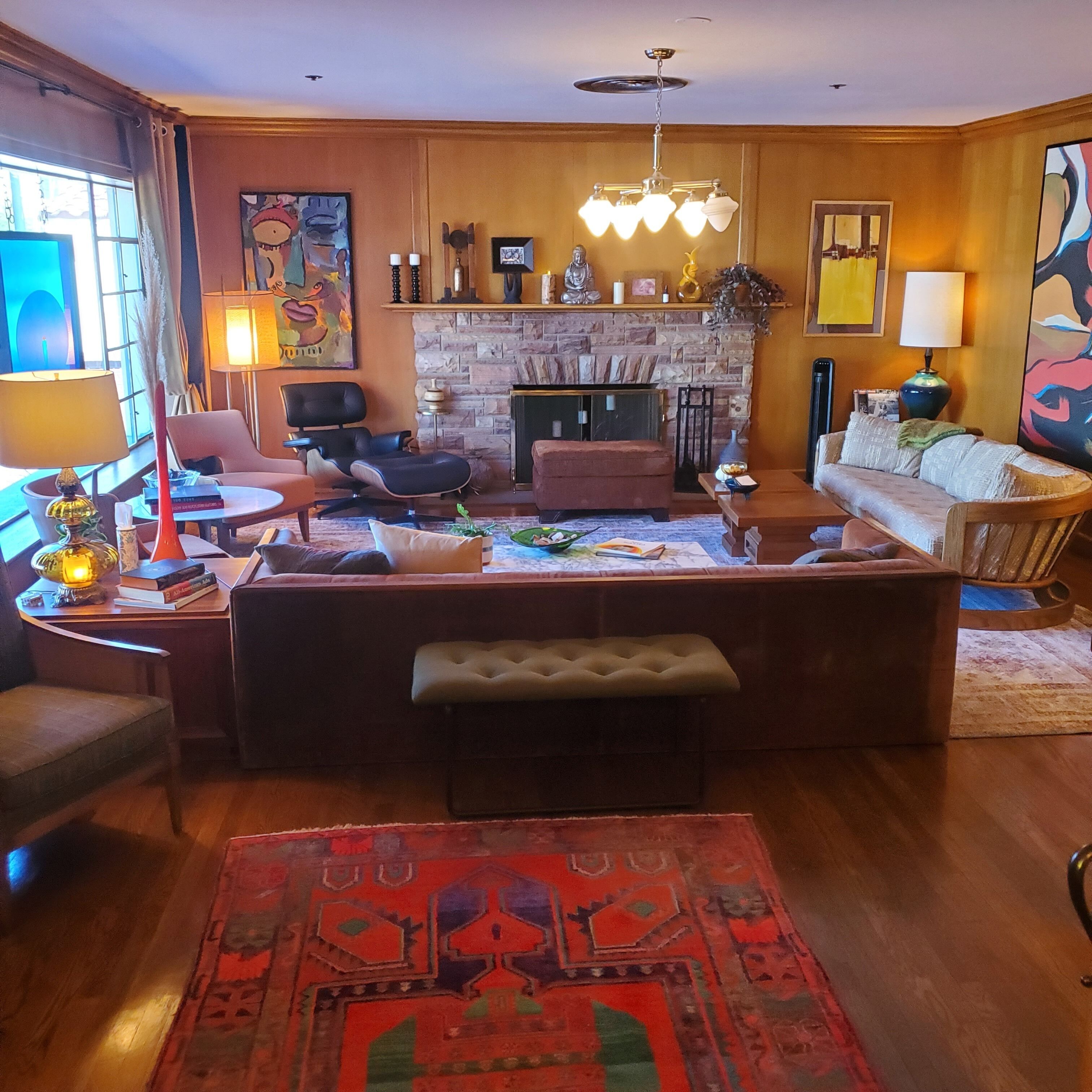 A cozy living room with a fireplace, comfortable seating, and a large rug.