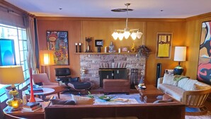 Un salon chaleureux avec une cheminée, des fauteuils confortables et un grand tapis.