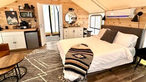 A cozy bedroom with a bed, bedside table, and a view of the kitchen. - The Laredo, Luxury Safari Tent (Cadiz)