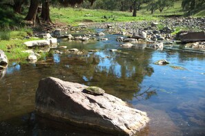 A clear stream with rocks and trees in the background. - Little House in the Nursery (Wallabadah)