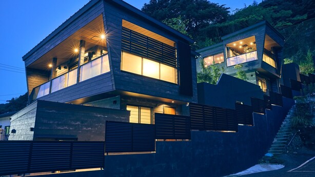Una casa moderna de dos pisos con ventanas amplias y un balcón.