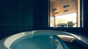 Un baño moderno con una bañera grande, techo de madera y vista a una barbacoa exterior.
