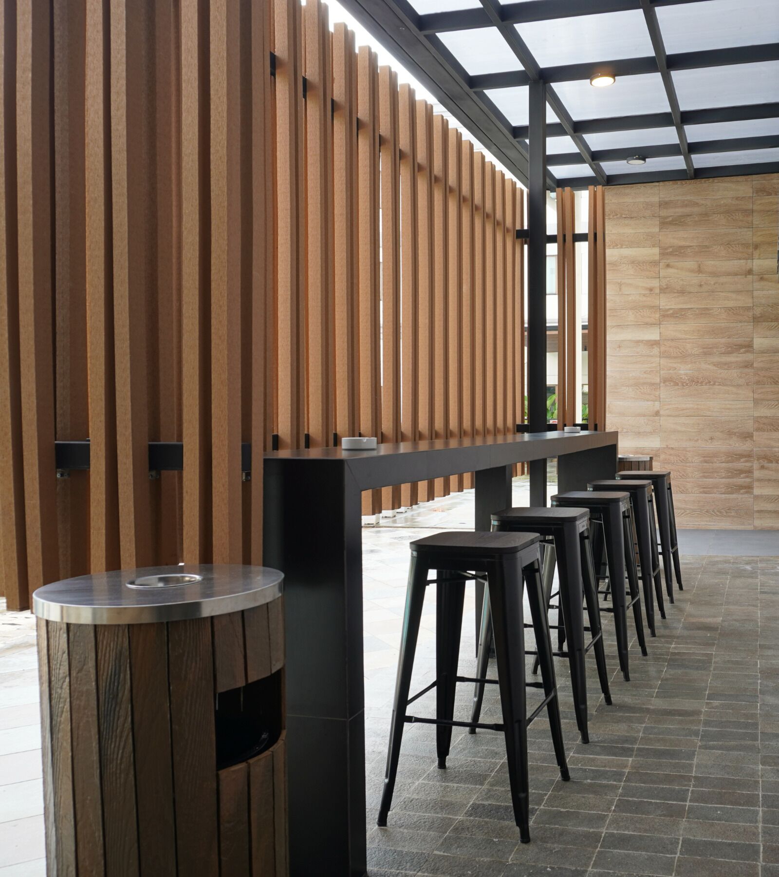 Un área de estar moderna al aire libre con una larga barra y varios taburetes.