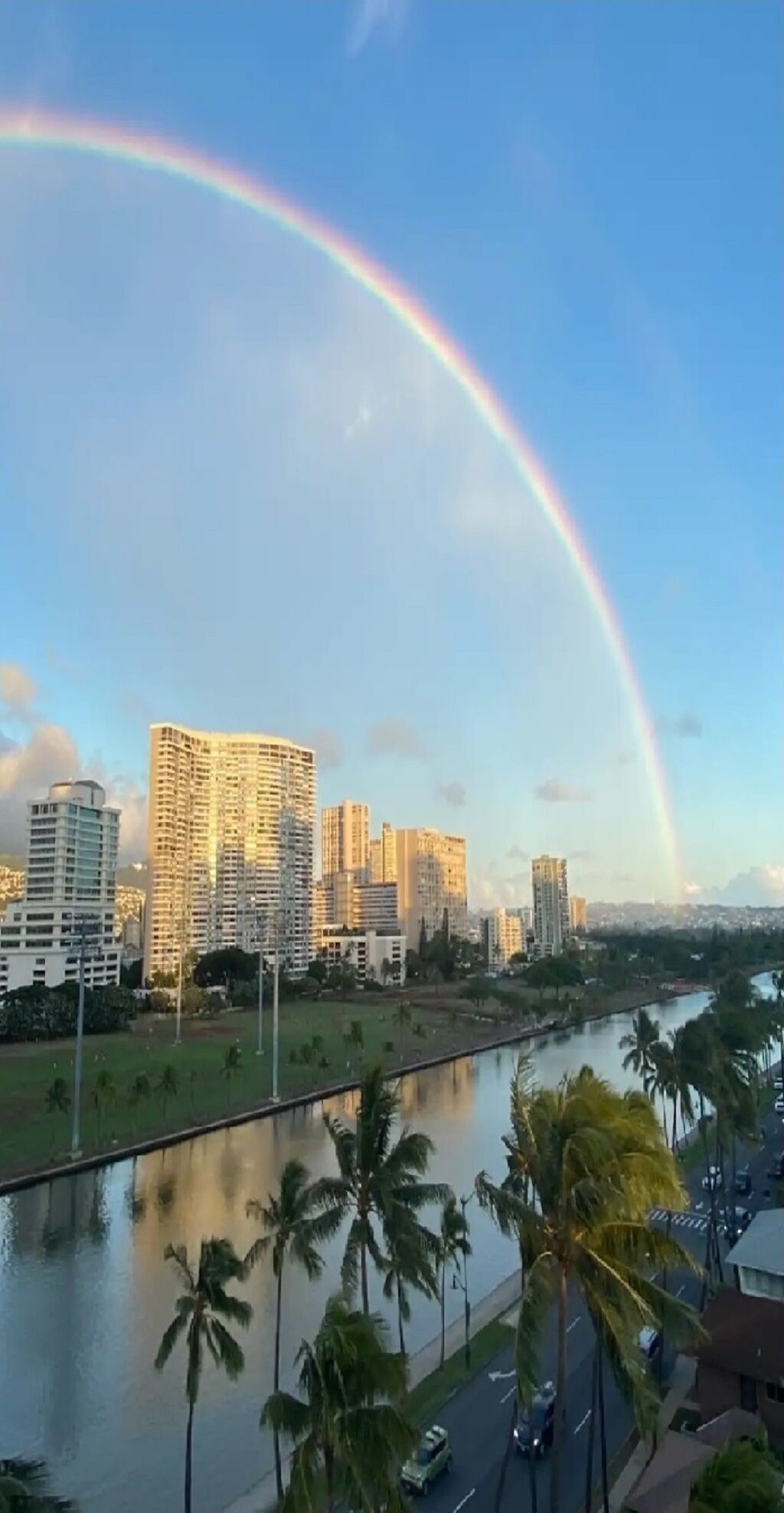 Panorama urbano con grattacieli, un fiume e un arcobaleno.
