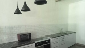 A kitchen with white cabinets, a black countertop, a built-in oven, a dishwasher, and a sink. - Villa Mertanadi 18 (Seminyak)