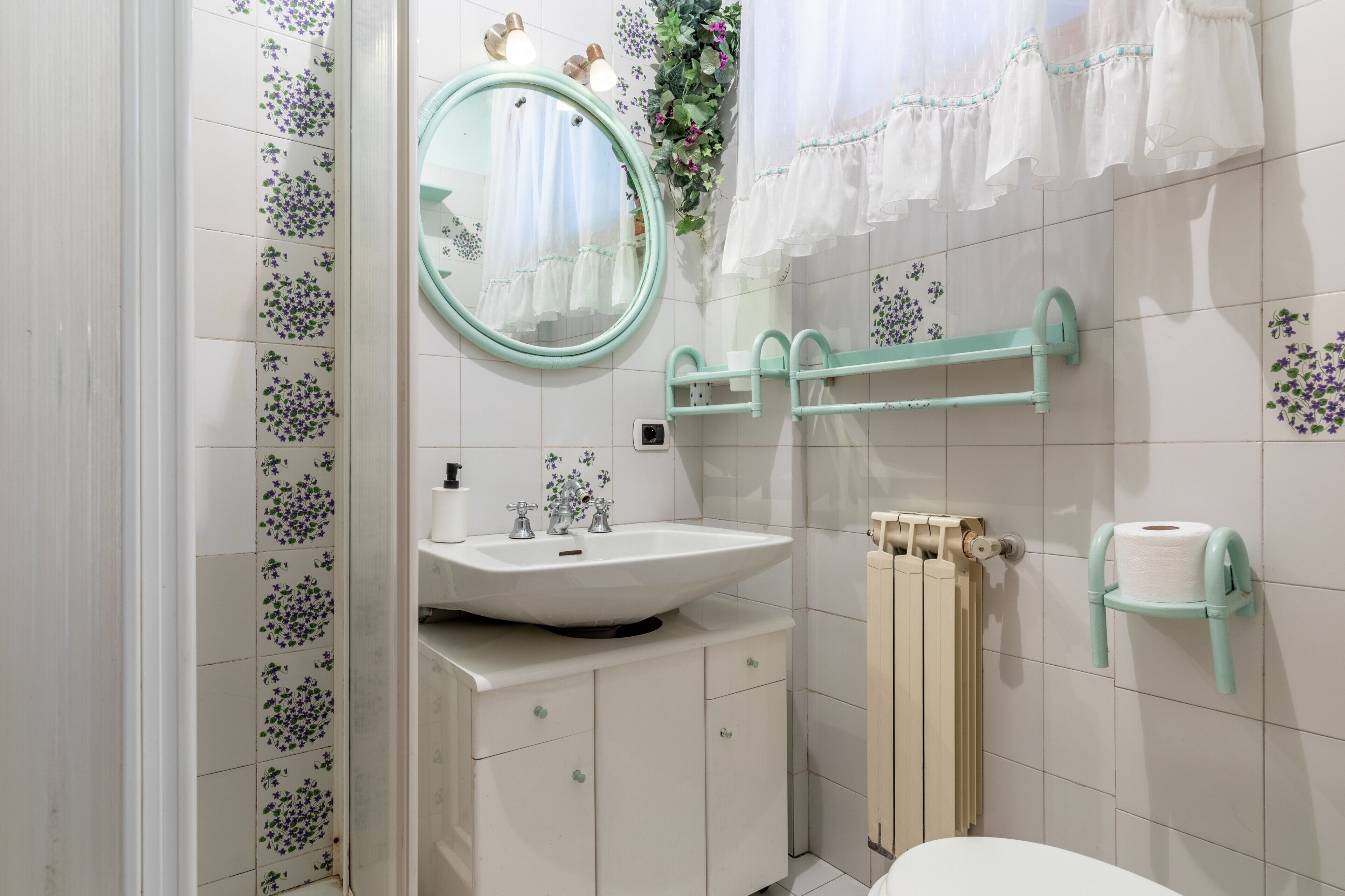 Een badkamer met een wit wastafelmeubel, een ronde spiegel, een toilet en een handdoekhouder.