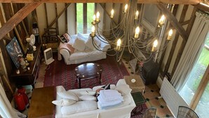 A rustic room with a wooden ceiling, a white sofa, a small table, and a chandelier with multiple candles. - Beautiful one Bed Barn in national park 1 hr from London with small pool (Petworth)
