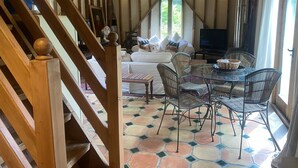 A cozy living area with a sofa, a dining table with chairs, and a staircase leading to an upper level. - Beautiful one Bed Barn in national park 1 hr from London with small pool (Petworth)