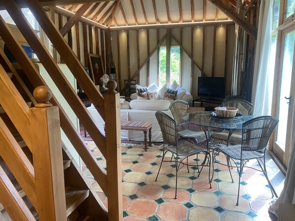 A cozy living area with a sofa, a dining table with chairs, and a staircase leading to an upper level.