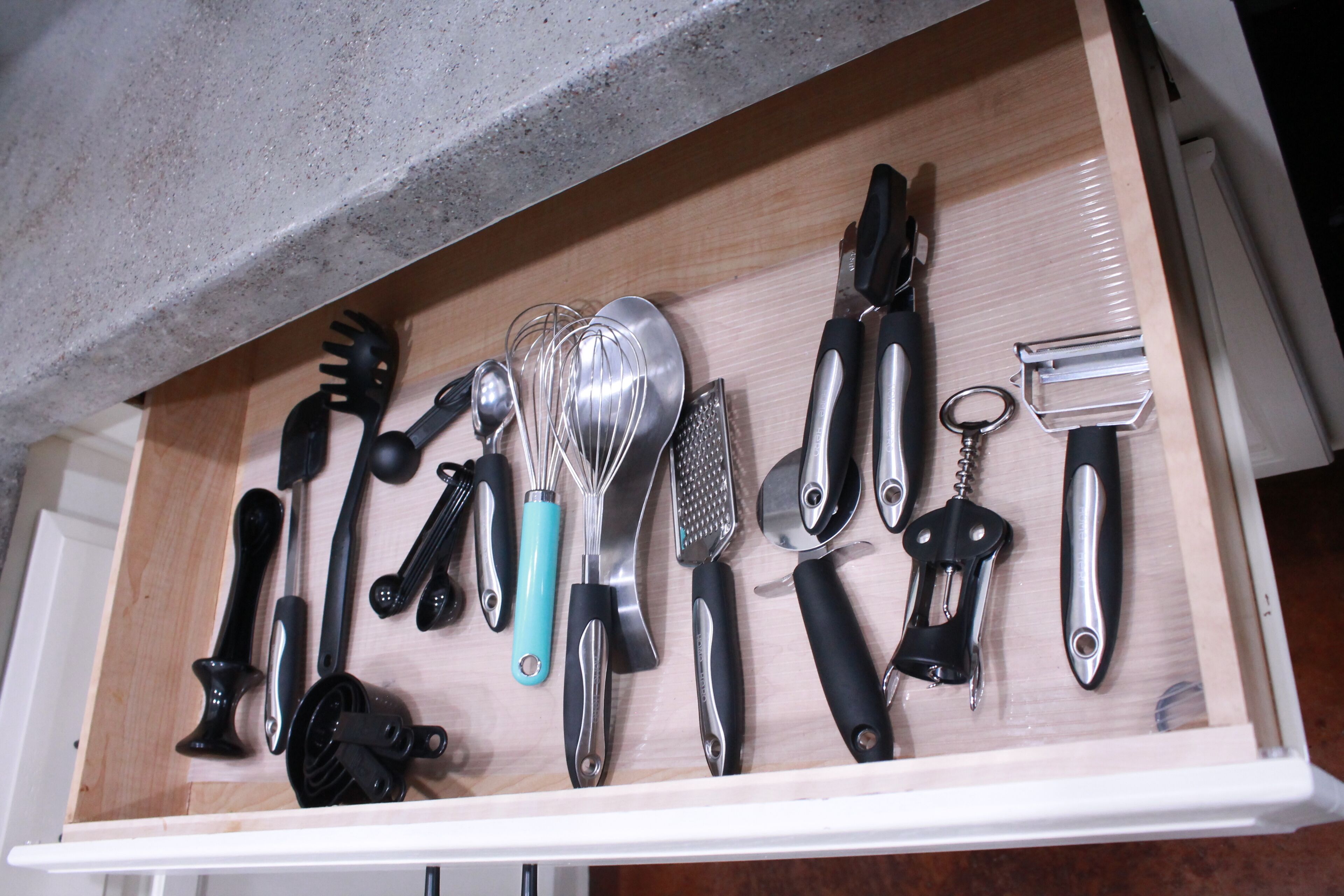 A kitchen drawer with various utensils and kitchen tools.