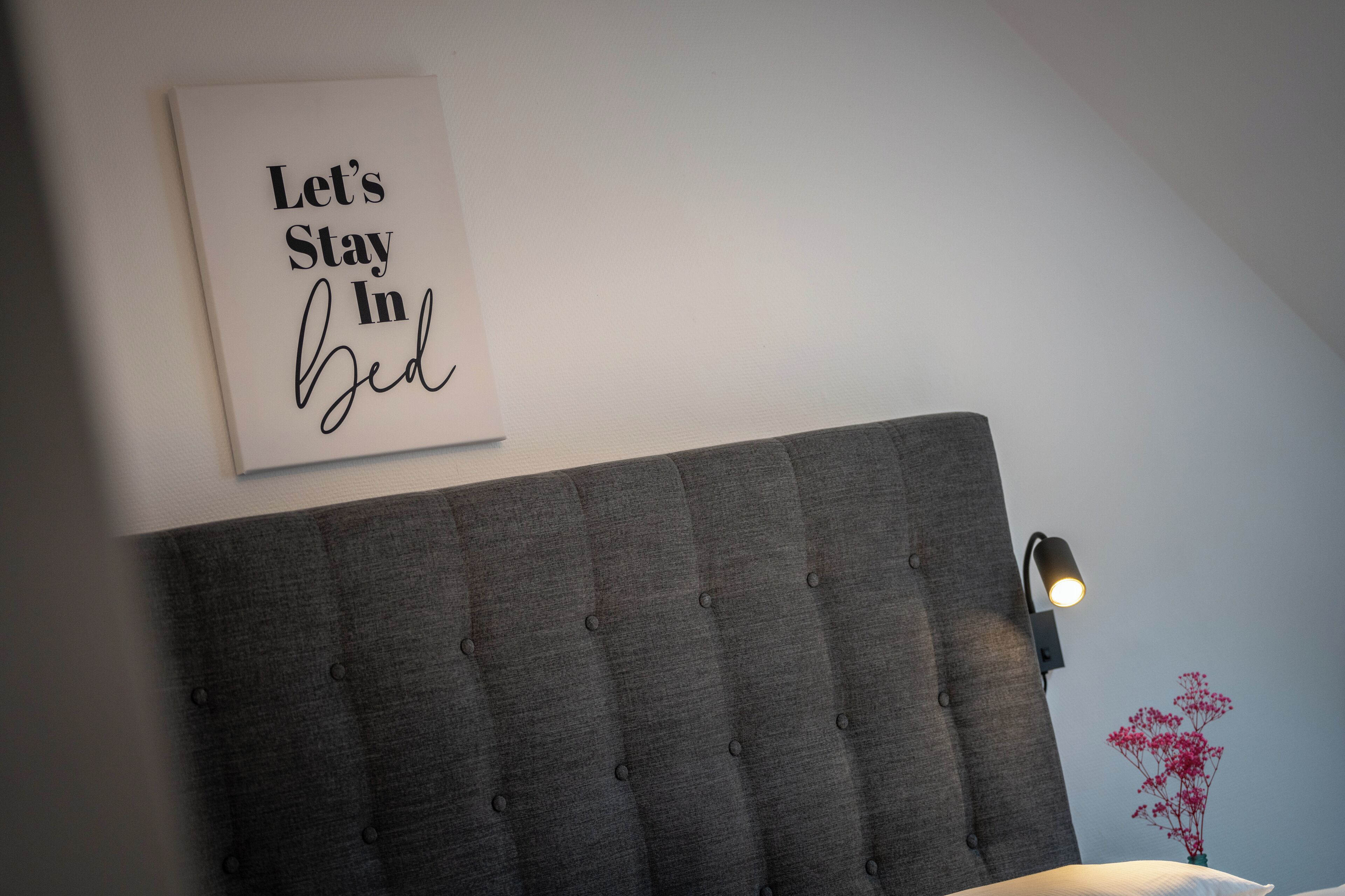 Une chambre à coucher avec une tête de lit, un panneau décoratif fixé au mur et une lampe de chevet.
