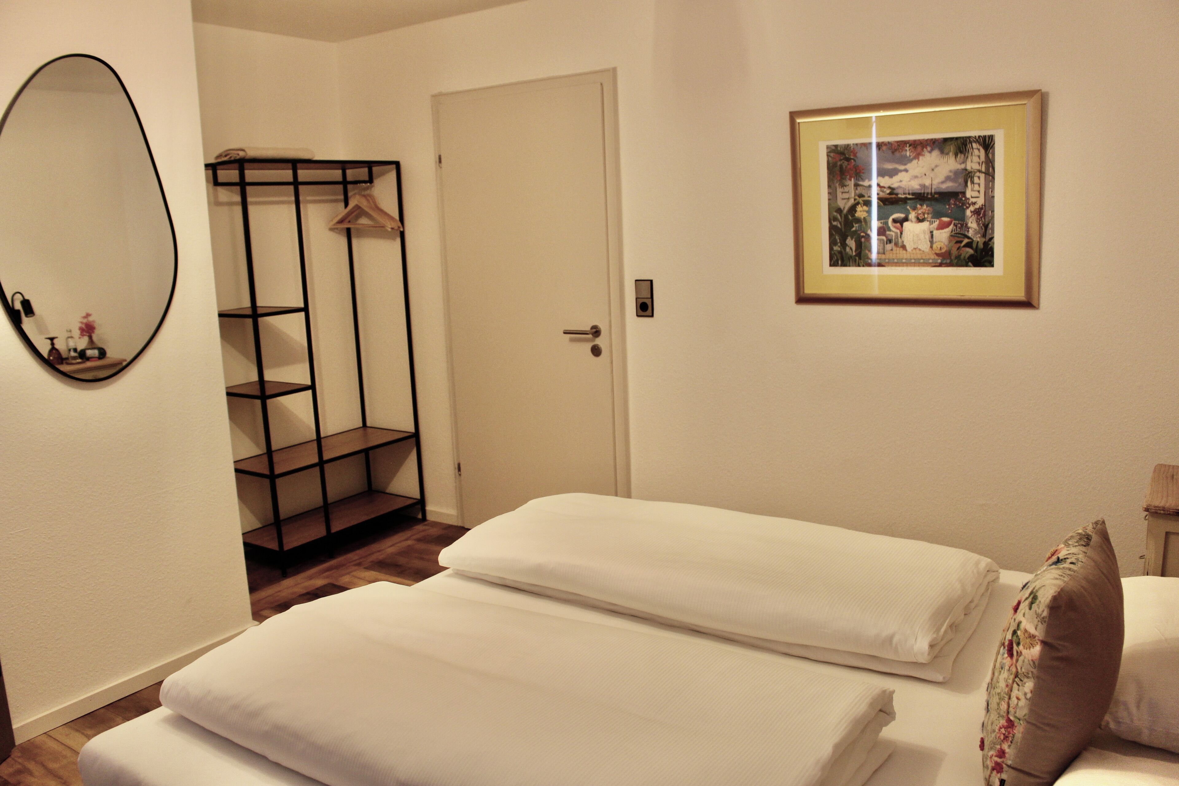 Una habitación de hotel con una cama, un armario, un espejo y un cuadro en la pared.