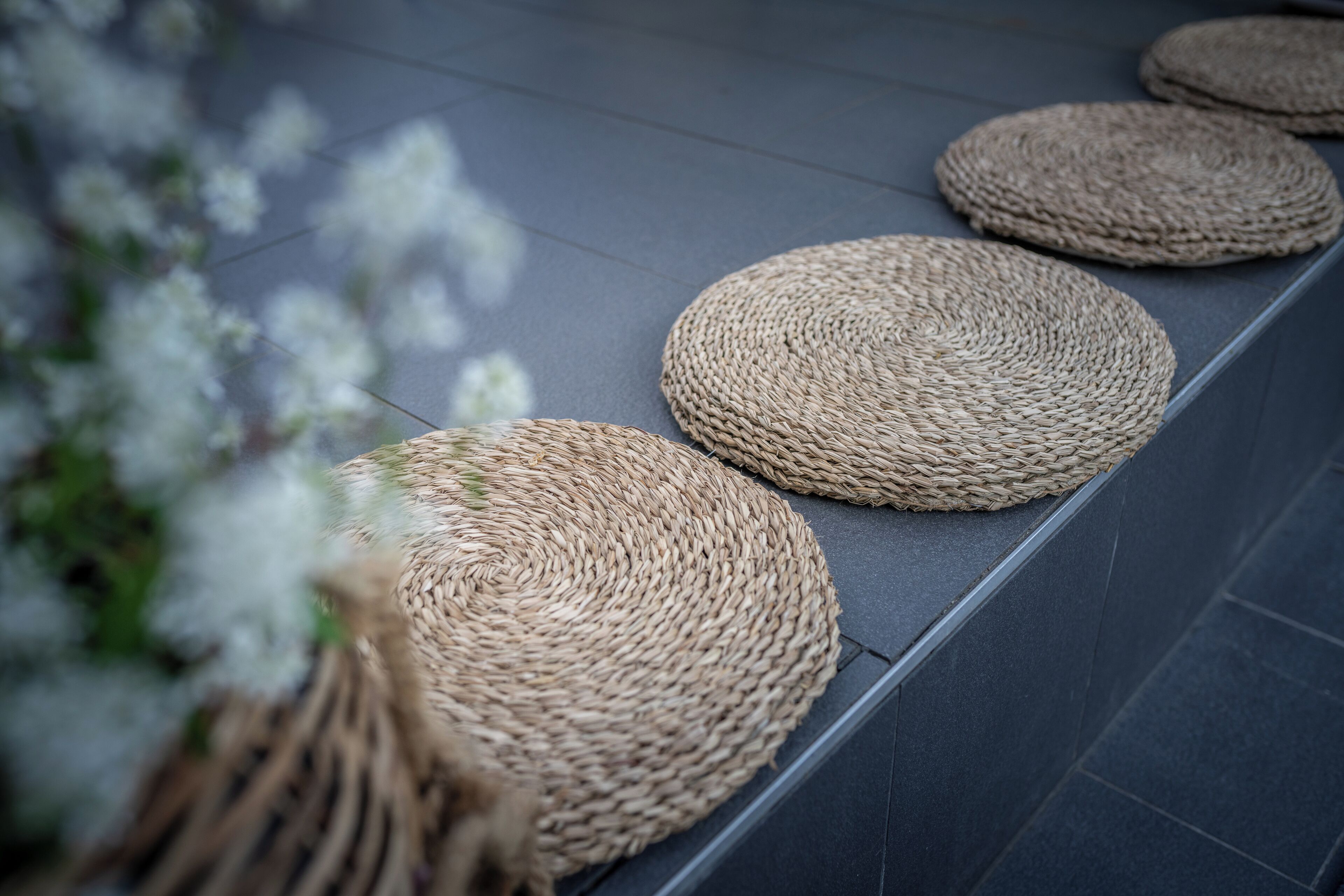 A series of woven mats on a tiled floor.