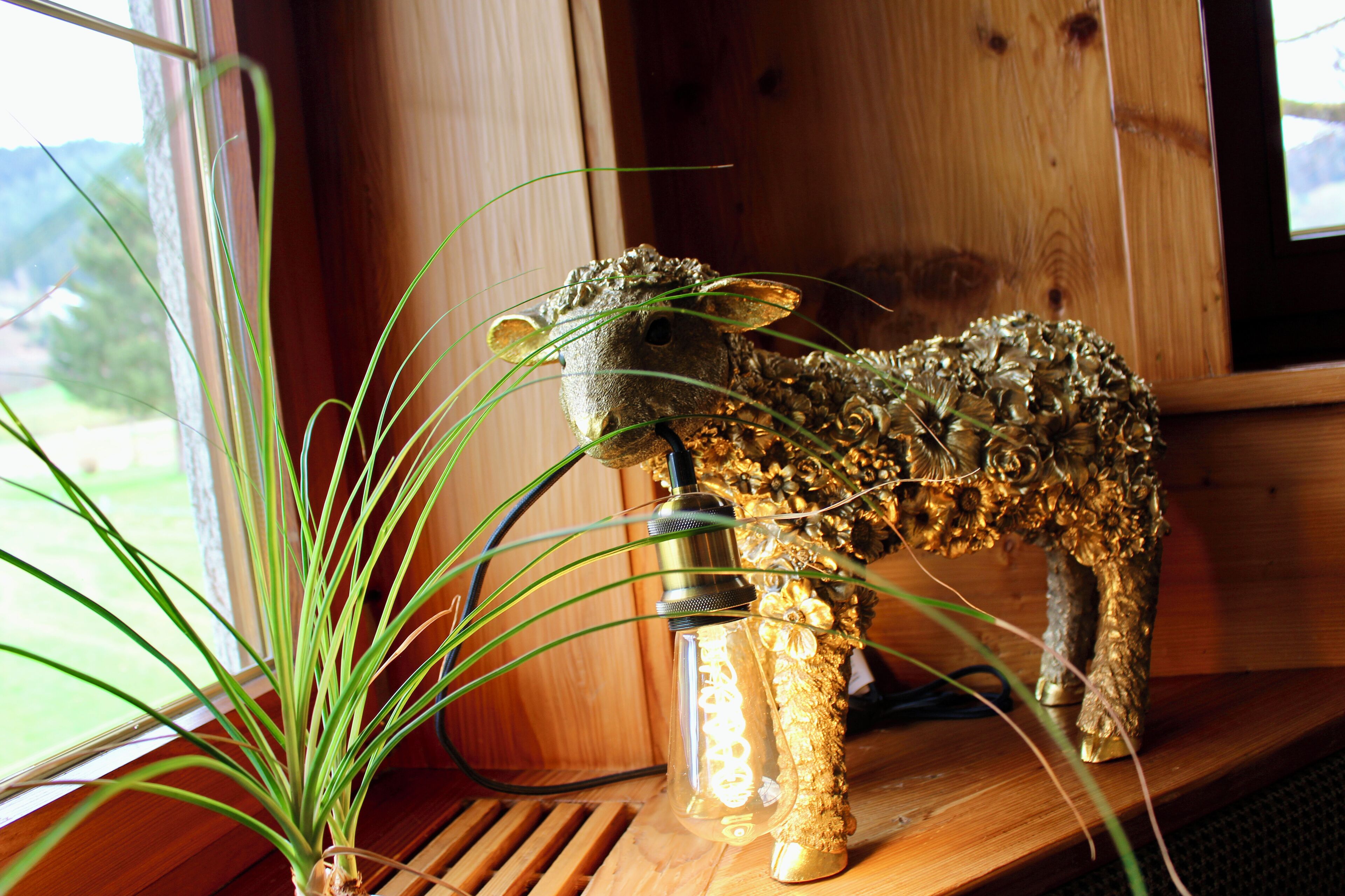 A decorative animal figurine on a wooden shelf near a window.