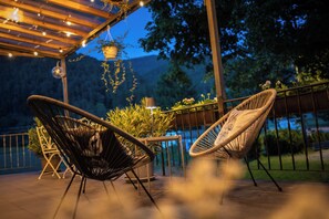 A patio with two wicker chairs, a table, and hanging plants under a wooden pergola. - Engel 16 - Adults Only (Gutach)