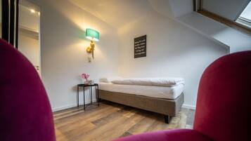 Een slaapkamer met een bed, nachtkastje, lamp en een muur met een motiverende quote.