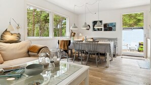A modern living room with a sofa, dining table, and kitchen area.