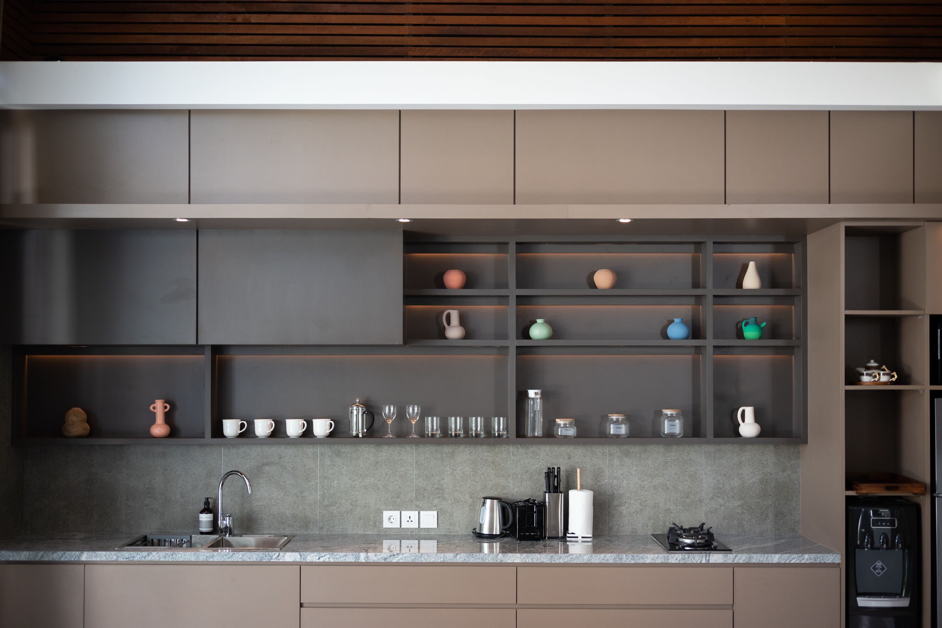 Una cocina moderna con armarios grises, encimera de granito y varios electrodomésticos.