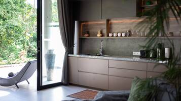 Una cocina moderna con un ventanal grande, estanterías empotradas y una zona de comedor con una silla acolchada.